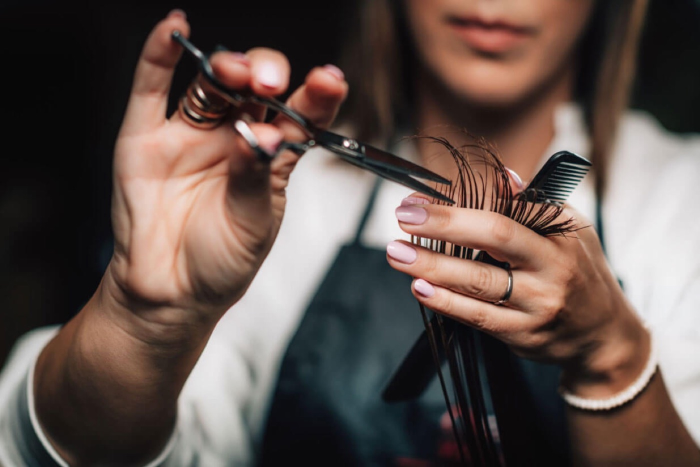 Friseurin schneidet eine Haarsträhne mit Schere und Kamm