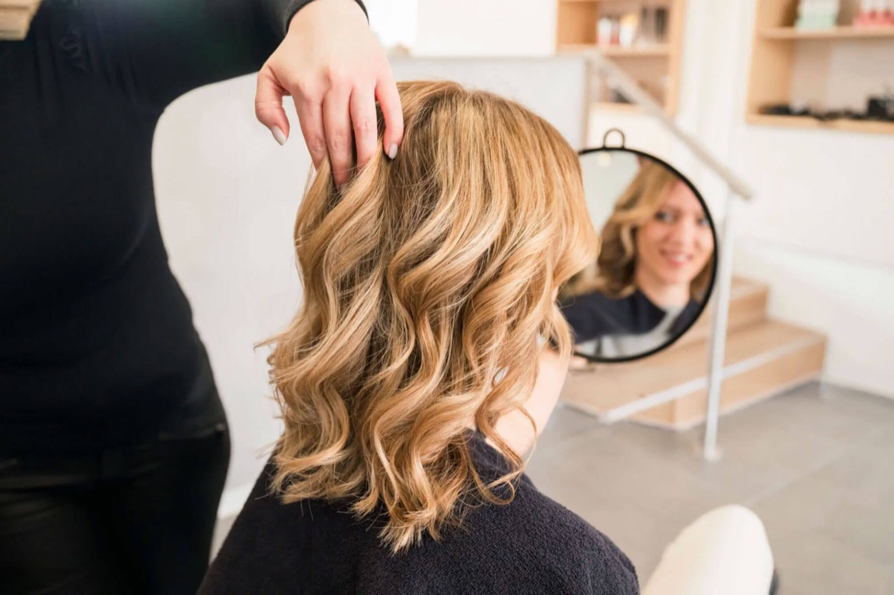 Friseurin zeigt einer Kundin die fertige Frisur im Spiegel